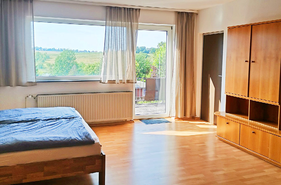 Das Elternzimmer mit Doppelbett und Zugang zum Balkon auf dem Campingplatz Prahljust im Harz