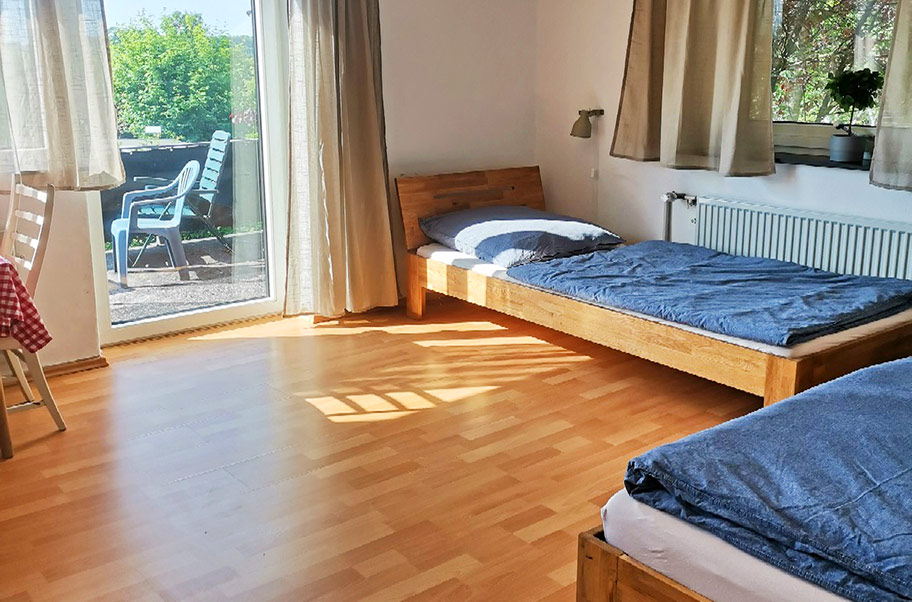 Das Kinderzimmer mit zwei Betten in der Ferienwohnung mit Zugang zum Balkon